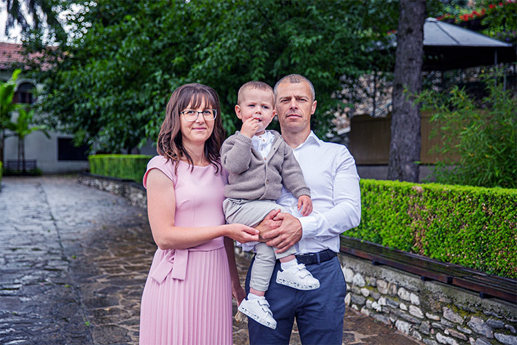 Родители с детето си застанали за снимка след кръщене в двора на Белащински манастир Свети Георги Победоносец.