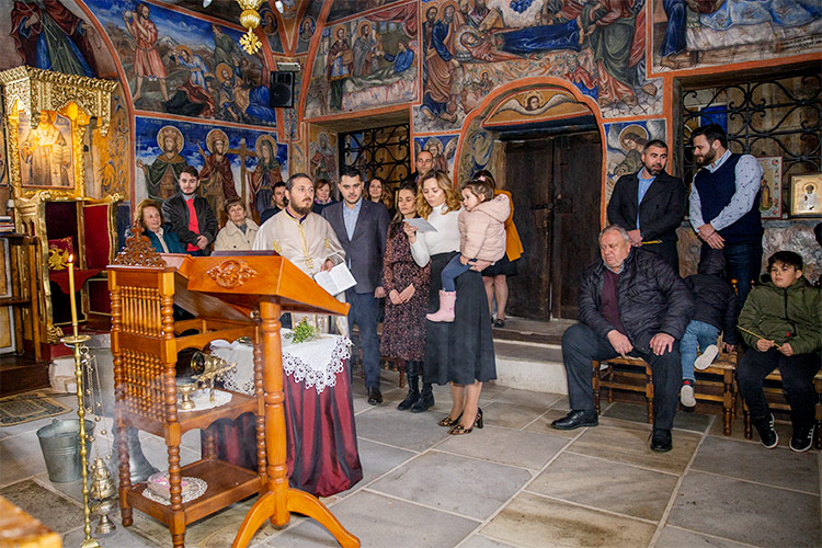 Ритуал Свето Кръщение в Кукленски манастир Св. Св. Козма и Дамян. Кръстницата чете част от требника по време на ритуала.