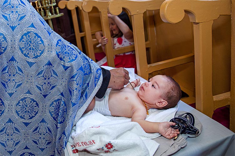 Отецът помазва момченцето с елей след кръщаване в купела по време на ритуал Свето Кръщение в храм Свети Свети Константин и Елена, село Браниполе.