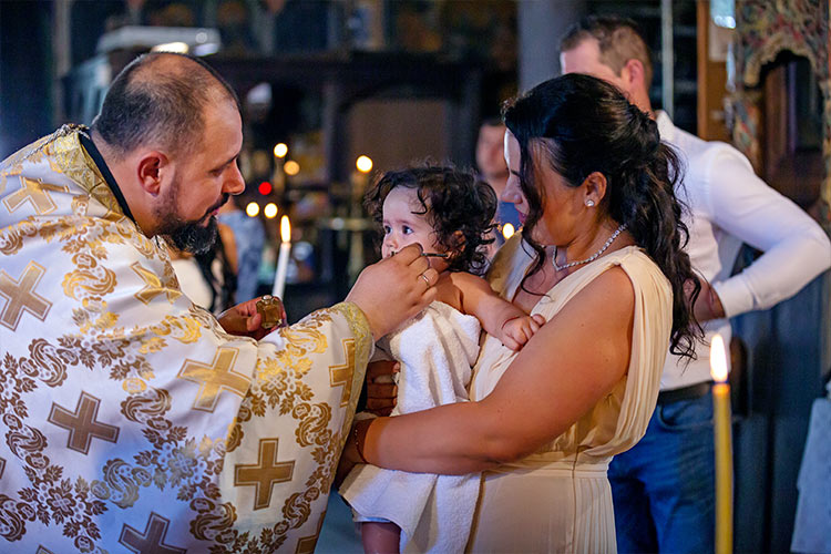 Отецът помазва момиченцето с елей след кръщаване в купела по време на ритуал Свето Кръщение в храм Свети Свети Константин и Елена, град Пловдив.