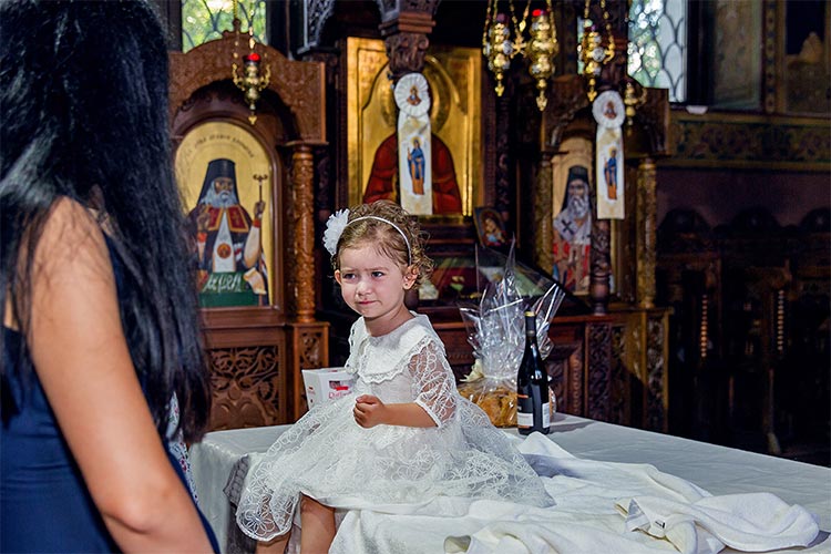 Новопокръстено момиченце облечено в новата си бяла рокличка след кръщаване в купела по време на ритуал Свето Кръщение в храм Света Преподобна Петка. град Пловдив.