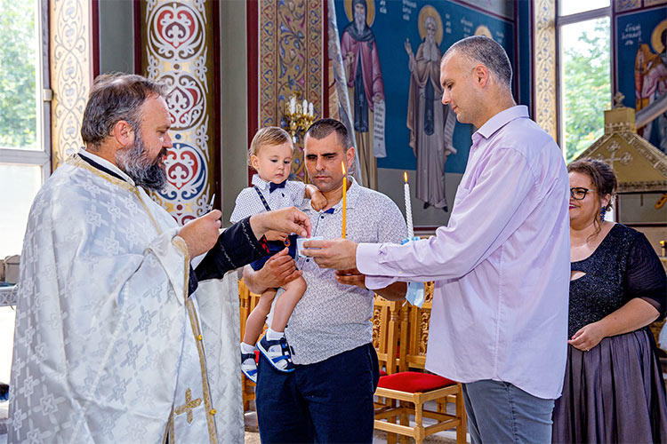 Отецът отрязва кичур коса от новопокръстено момченце по време на ритуал Свето Кръщение в храм "Свети Николай Мирликийски Чудотворец", град Пловдив.