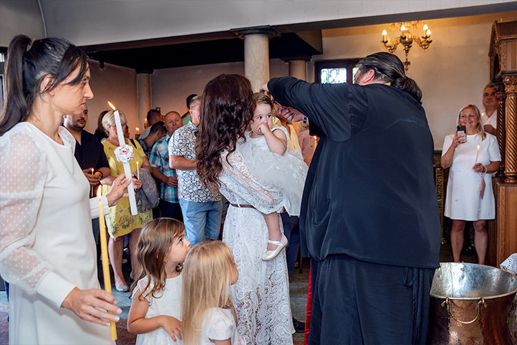 Отецът отрязва кичур коса от новопокръстено момиченце по време на ритуал Свето Кръщение в храм "Света Троица", Кръстова Гора.