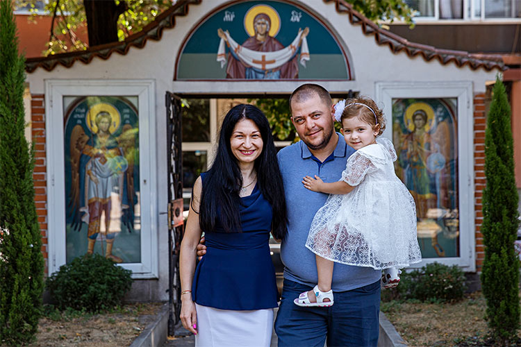 Майка и баща с новопокръстеното си момиченце след края на кръщението му в двора на храм Света Преподобна Петка, град Пловдив.